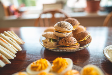 Delicious easter brunch with homemade sandwiches, buns and filled eggs on a wooden kitchen table 