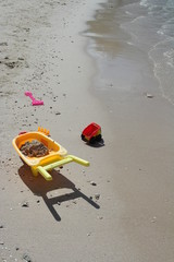 Children's plastic, shovel, wheelbarrow, truck on the beach. Children's beach toys on the sand on a sunny day.