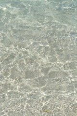 Transparent turquoise sea water, natural background. Sea surface in a turquoise lagoon. The texture of sea water. Summer and travel vacation concept.