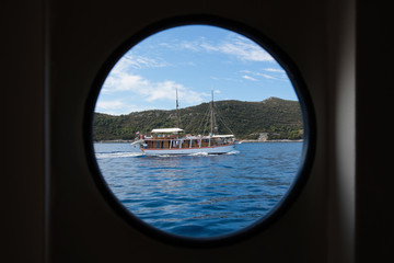 Obraz na płótnie Canvas A wooden tourist ship sailing photographed through a silhouette of a ships window