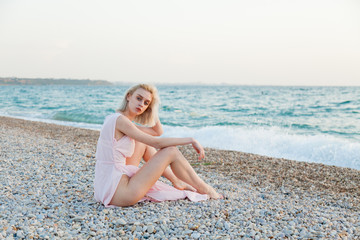 Fototapeta na wymiar Portrait of a beautiful fashionable blonde woman on an empty beach by the sea