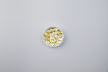 Vitamin D3 gelatin capsules on a white background. The fat-soluble solar vitamin cholecalciferol glows yellow and glistens. Place for text