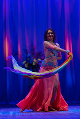 Dancer with long hair in orange neon  oriental costumes dance belly dance on the concert stage