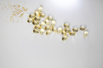 Vitamin D3 gelatin capsules on a white background. The fat-soluble solar vitamin cholecalciferol glows yellow and glistens. Place for text