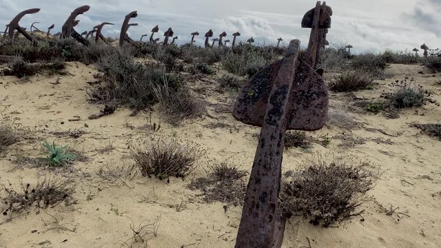 Rusty old anchors on the beach at the Anchor Cemetery graveyard at Praia do Barril beach, in Tavira, Algarve, Portugal