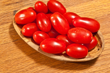 top, view, close up, of a rare wood bowel filled with local, ripe, cherrry tomatoes,  on a wood cutting board