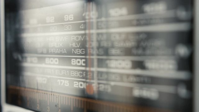 Tuning on Rome station in an old analog vintage fashion portable home radio with city names and frequencies numbers close up