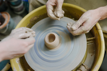 hands make a vase behind a potter's wheel. ceramics. pottery, macro shooting