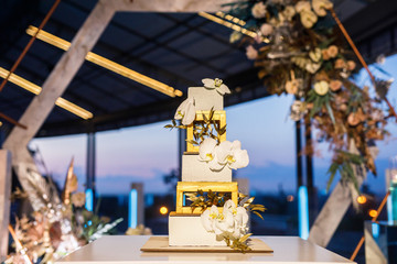 night wedding ceremony, the arch is decorated with flowers, candles and garlands of light bulbs and there is a wedding cake on the table