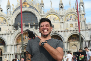 Fototapeta na wymiar Laughing man with a bird on his shoulder - Venice