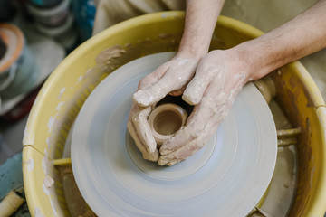 hands make a vase behind a potter's wheel. ceramics. pottery, macro shooting