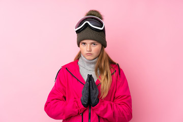 Ukrainian teenager skier girl with snowboarding glasses over isolated pink background pleading