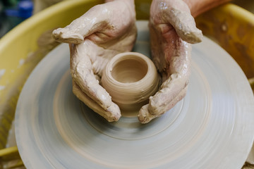 hands make a vase behind a potter's wheel. ceramics. pottery, macro shooting
