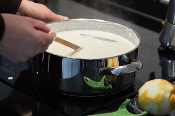 Woman's hands cooking with a wooden spoon in a pot