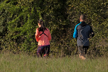 Jogging d'couple homme et femme courant sur une route de campagne en tenue fluo au printemps.