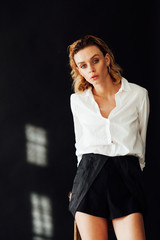 Portrait of a beautiful fashionable blonde woman in black shorts and white shirt © dmitriisimakov