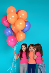 Smiling little children girls posing with bright colorful air balloons on blue background. friends having fun on birthday party.