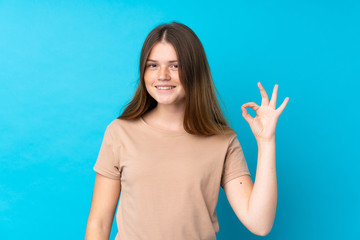 Ukrainian teenager girl over isolated blue background showing ok sign with fingers