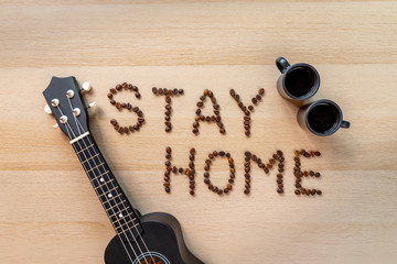 Inscription stay home with coffee beans with cup of coffee and ukulele