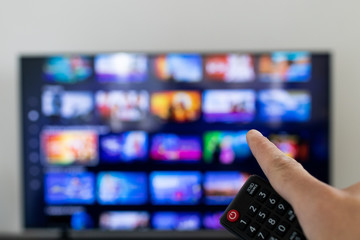 Tv remote controller in hand of customer looking for some content in Smart Tv app for streaming...