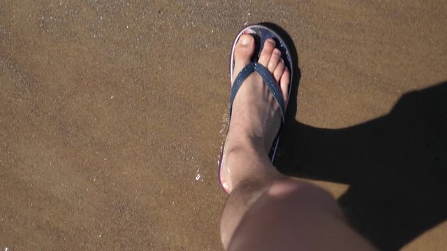 Point of view Young Man Flip Flops Walking golden Sand Sea Beach. Male Legs steps near Ocean Sandy shore Waves. Sunny Summer slow motion. Isolated close-up POV