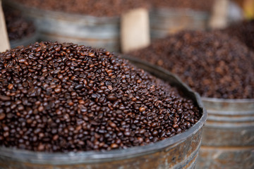 Heap of coffee bean with blurred background of coffee barrels, macro