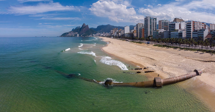 Strong tidal wave destroyed and washed away the sand of Ipanema beach revealing a large pipeline construction leading from the neighbourhood into the ocean with the Two Brothers mountain in the back