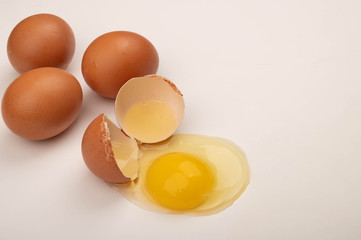 A broken chicken egg and scattered eggs on a white background. Close up.