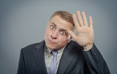 Closeup portrait of happy bashful socially awkward young man waving with hands, isolated. Positive...