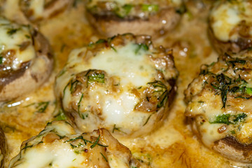 Mushrooms baked in the oven with cheese, green onions and dill. Close up.