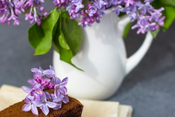 Spring composition with lilac flowers and brownie, wet cake. Dessert for served for tea or coffee break. Snack on a spring day in the garden.