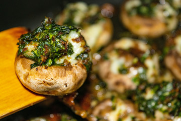 Mushrooms baked in the oven with cheese, green onions and dill. Close up.