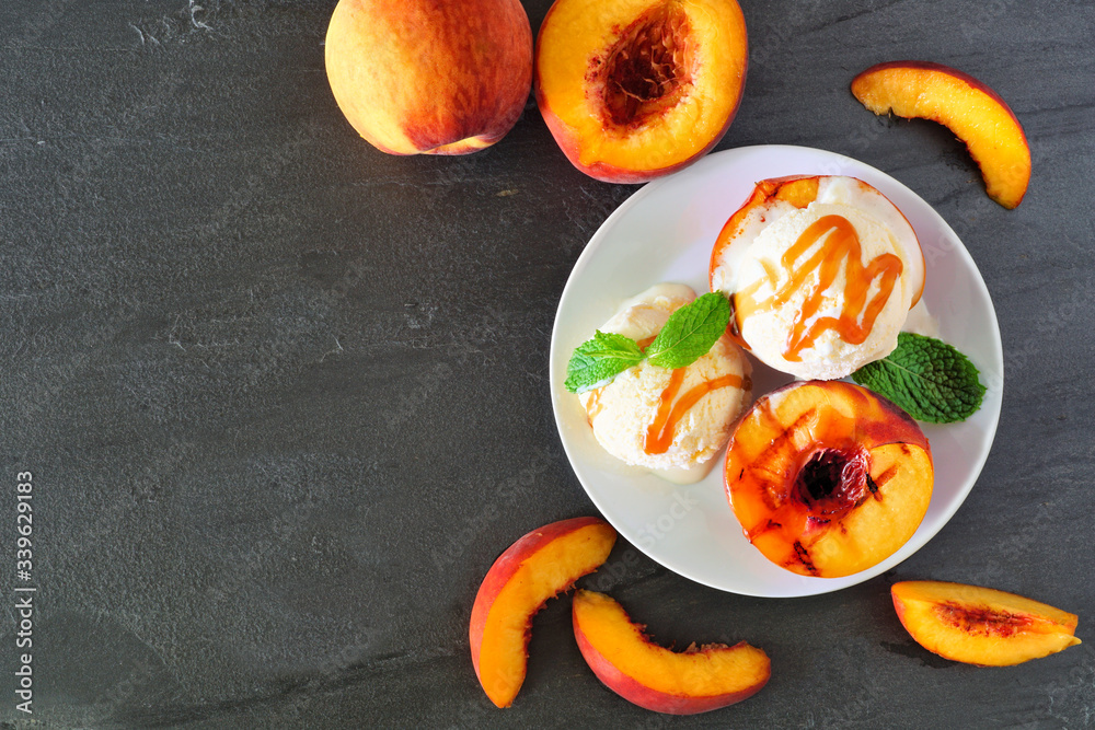 Aufkleber Summertime grilled peaches with vanilla ice cream and caramel sauce. Overhead view table scene on a dark slate background with copy space.