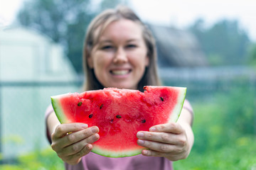 Joyful woman holds a slice of watermelon in front of her. Summer holiday concept. Healthy eating....