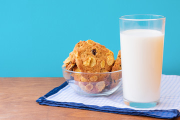 Pile of freshly baked biscuits with cereal and raisins and glass of milk on blue towel. Concept of healthy snack and tasty breakfast.