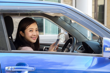 Asian woman using smart phone in a car on the road