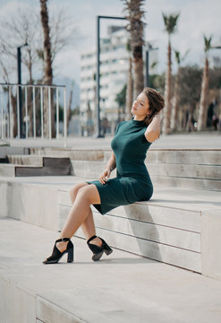 A beautiful young brunette girl is walking in the city posing for the camera. Sunny weather and promenade in Antalya