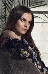 Fototapeta premium Portrait of pretty girl with natural make up and wearing floral pattern dress and sitting in sun