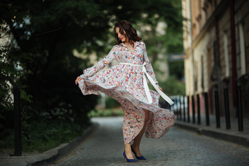 Beautiful brunette sexy tourist girl walking on busy city street with long hair flying in the wind.