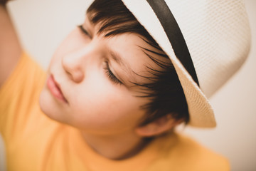 Portrait of a beautiful fashionable boy in a hat in summer on a summer day with a relaxing expression on his face. Close-up.