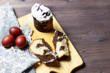 easter chocolate cake pieces on wooden board, textile table cover, colored eggs