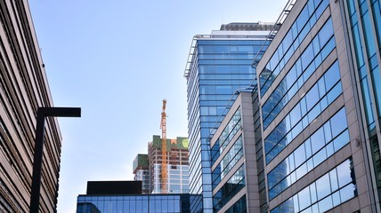 Naklejka premium Blue curtain wall made of toned glass and steel constructions under blue sky. A fragment of a building.