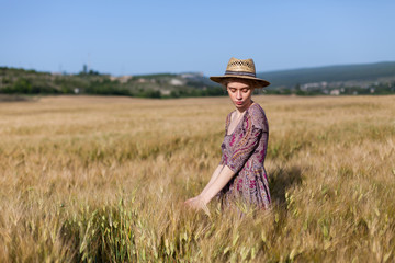 Naklejka na ściany i meble Portrait of a beautiful fashionable blonde woman in a dress and a field of wheat