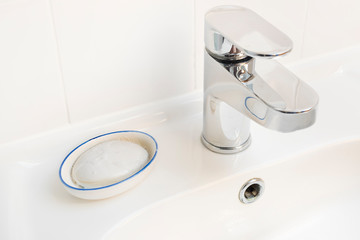 Close cropped photo of a wash basin which has a soap dish and silver coloured tap. 