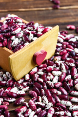 Violet with dots beans in wooden box with heart. Swallow beans. Vegetables for healthy eating. Organic food
