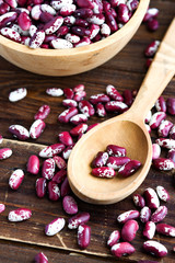 Violet with dots beans in wooden plate and spoon. Swallow beans. Vegetables for healthy eating. Organic food.