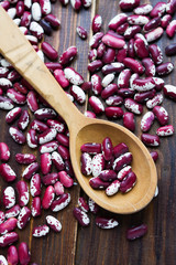 Wooden spoon and violet with dots beans on wooden background. Swallow beans. Vegetables for healthy eating.Organic food.