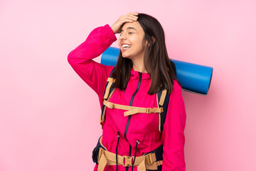 Young mountaineer girl with a big backpack over isolated pink background smiling a lot