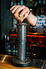 Fototapeta na wymiar Vertical image. Alternative Coffee Brewing Method. Close-up of the hands of barista, pouring ground coffee from a small cup into a coffee filter
