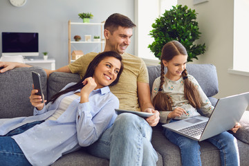 A happy family uses a laptop together while sitting at home.